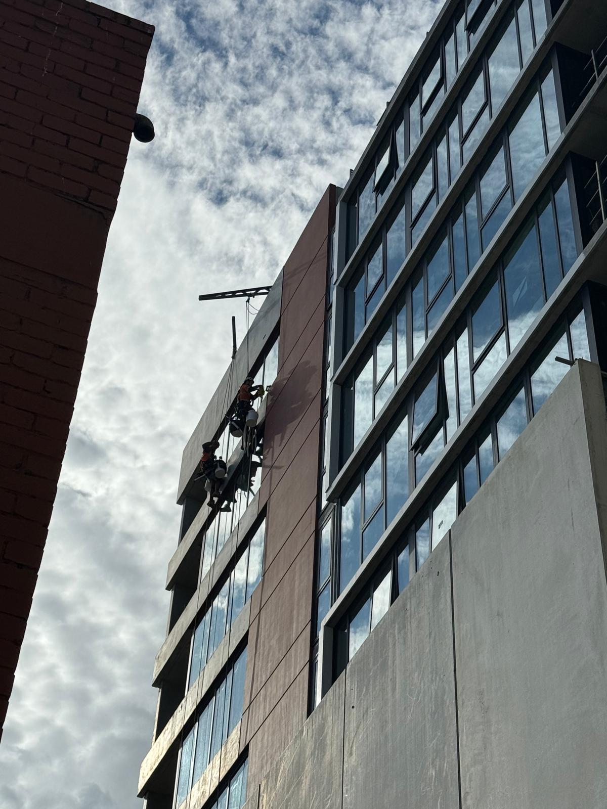 Two rope access technicians painting Melbourne high-rise building facade